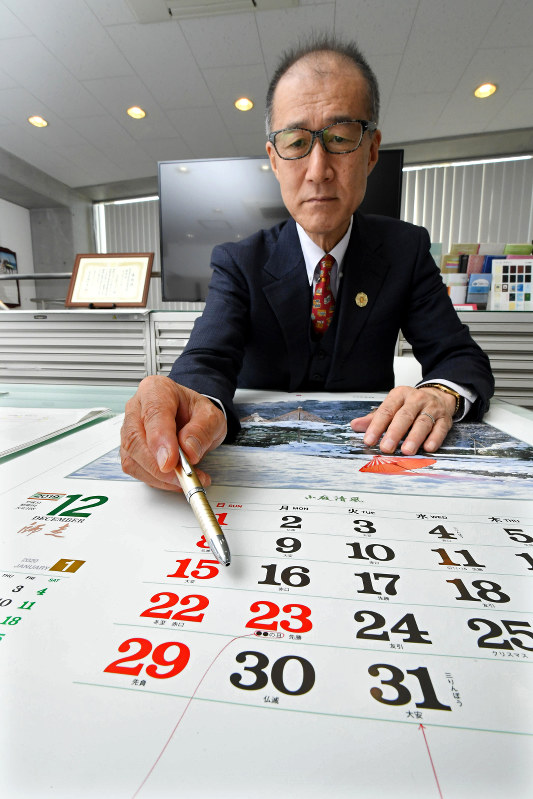 2018(平成30)年のカレンダーを指さす出版社「トーダン」の強口邦雄社長。天皇陛下の退位に伴う改元により、製作業者は対応を検討している=東京都荒川区で、根岸基弘撮影