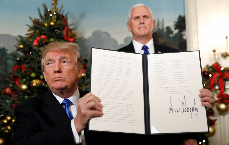 エルサレムをイスラエルの首都と認定すると宣誓した後、関連文書を掲げるトランプ大統領(左)。ペンス副大統領も同席した=ホワイトハウスで6日、ロイター