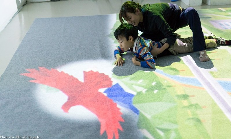 理学療法士に支えられながら、床に投映された鳥に触ろうと懸命に体を動かす岡田虎次郎さん(左)=東京都港区で11月5日、写真家・近藤浩紀さん撮影