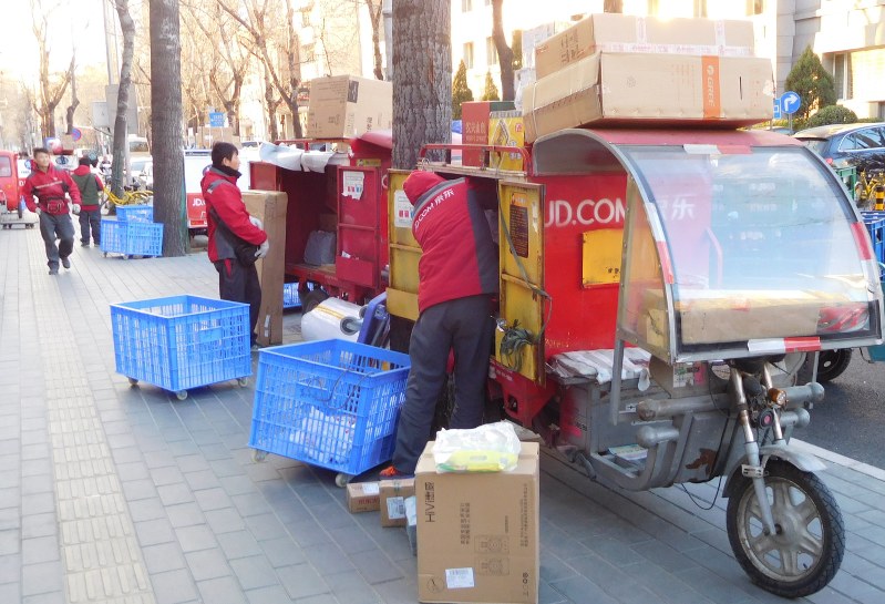 配達用の電動三輪車に荷物を載せる宅配員ら=北京市で2017年12月7日、河津啓介撮影