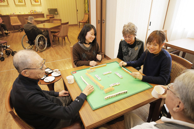 高齢者施設の交流イベントで、入居者とマージャンを楽しむ学生たち