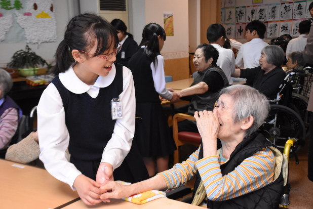 人は必ず年をとる。中学生のハンドマッサージを受ける高齢者施設の入所者