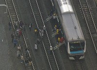 架線が断線した影響で線路上に停車するＪＲ京浜東北線の車両から線路に出る乗客ら＝神奈川県川崎市で２０１７年１２月１６日午後１時、本社ヘリから