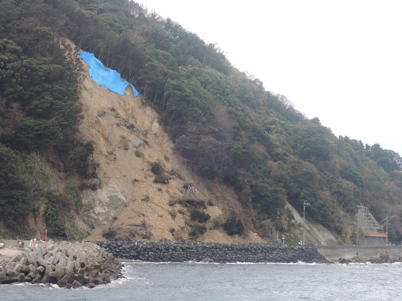 四浦地区の崖崩れ。海沿いの現場の県道では復旧工事が続く