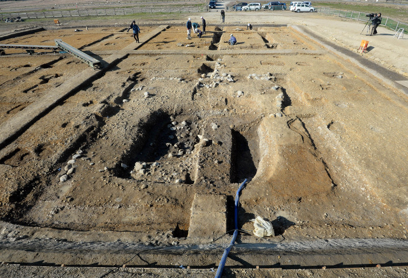 平城宮跡東院地区の発掘現場。手前の四角い大きなへこみが井戸の跡で、中央奥の炊事場跡へと溝が続く=奈良市で2017年12月21日、平川義之撮影