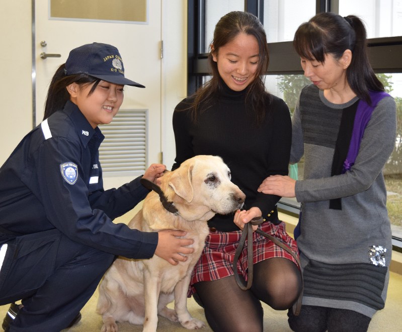 名古屋税関の女性ハンドラー(左)から、静岡県内在住の里親に引き渡される「ラブ号」=中部空港内の麻薬探知犬管理室で