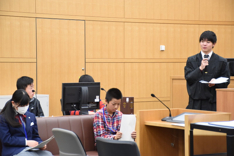 裁判官(右)の説明を聞きながら模擬裁判を進める中学生たち=千葉市中央区の千葉地裁で