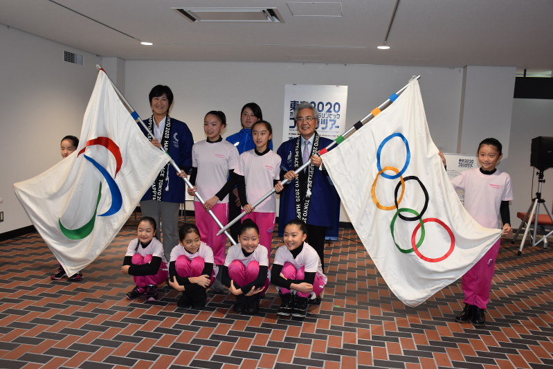 五輪旗・パラリンピック旗と一緒に記念撮影する葛西憲之市長や斎藤春香さんら=弘前市役所で