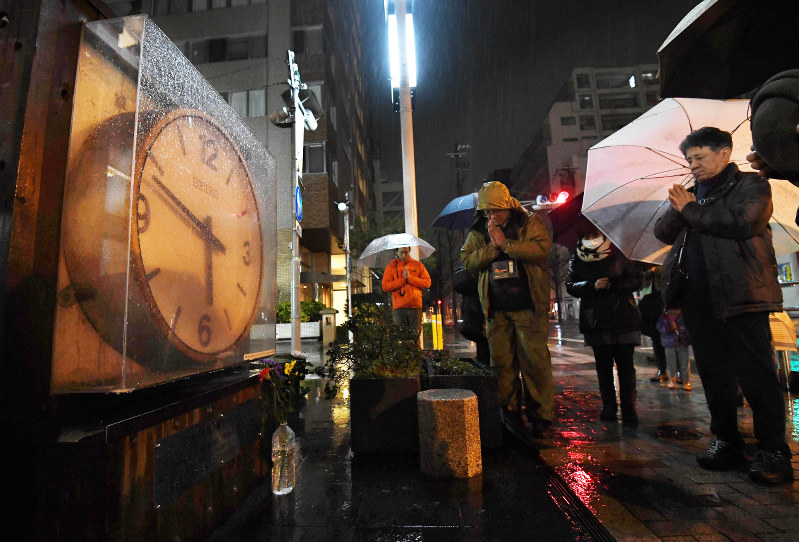 発生時刻で止まったままの時計の前で黙とうする人たち=兵庫県西宮市で2018年1月17日午前5時46分、平川義之撮影