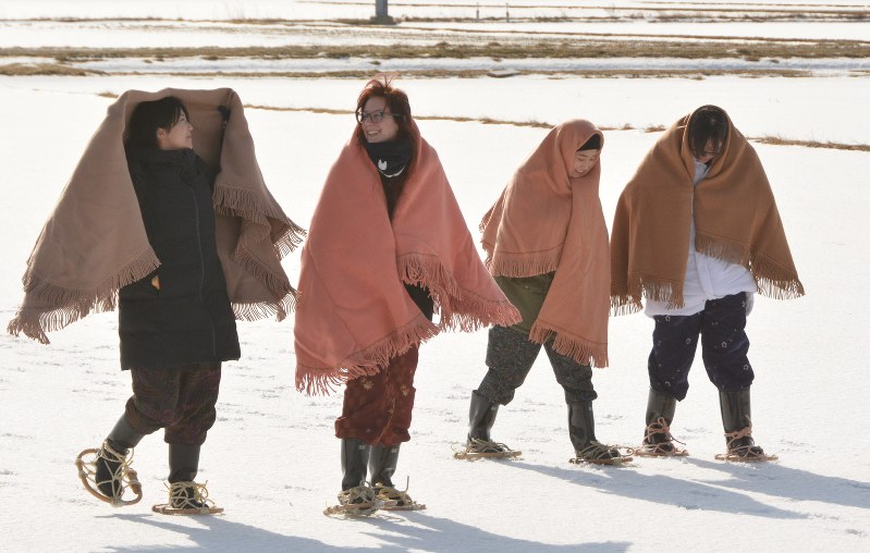 かんじきと角巻き姿で、雪原を歩く参加者たち=中泊町で