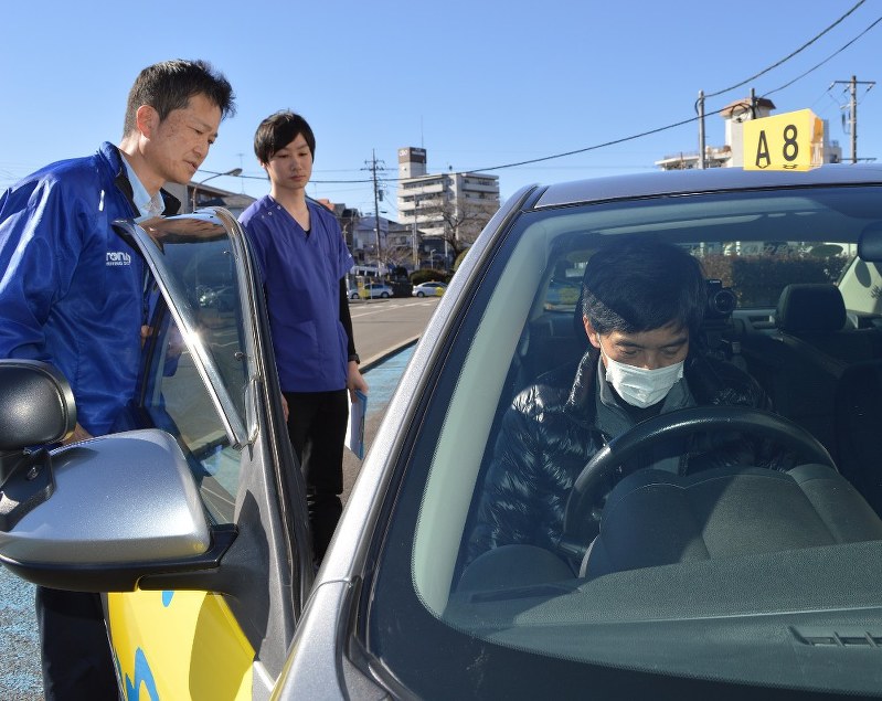 実車評価に取り組む男性(右端)。作業療法士の永島匡さん(中央)と教習所の山田浩・教習部統括課長が見守る=神奈川県座間市の都南自動車教習所で