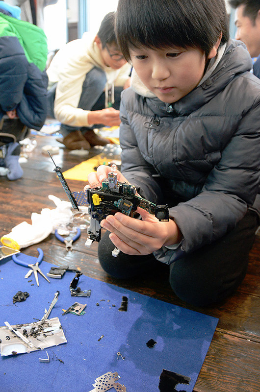 携帯ゲーム機を分解して作ったロボットのおもちゃを手に取る子供=福井県鯖江市旭町1のHana道場で、立野将弘撮影
