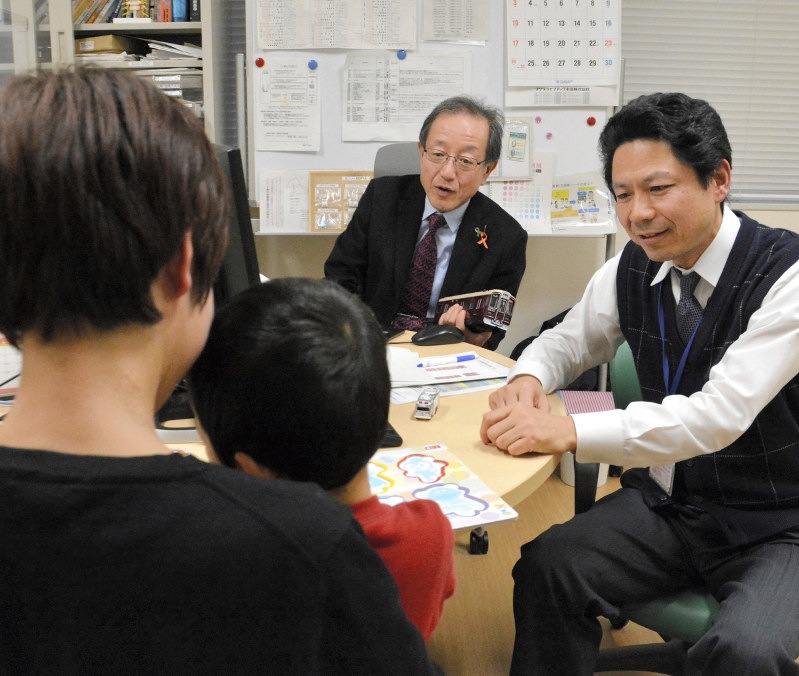 男児の診察をする前垣義弘医師(右)と、研修でその様子を見る岡空輝夫医師(右から2人目)=鳥取大医学部付属病院で