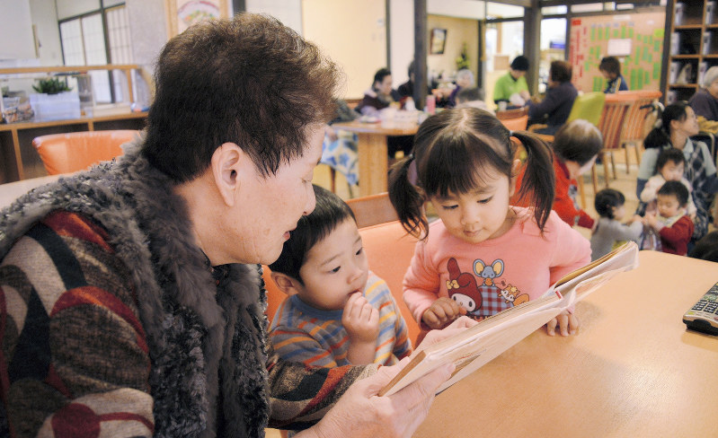 子供たちに絵本を読み聞かせするデイサービスセンター「梅本の里・小梅」の利用者(左端)=松山市で