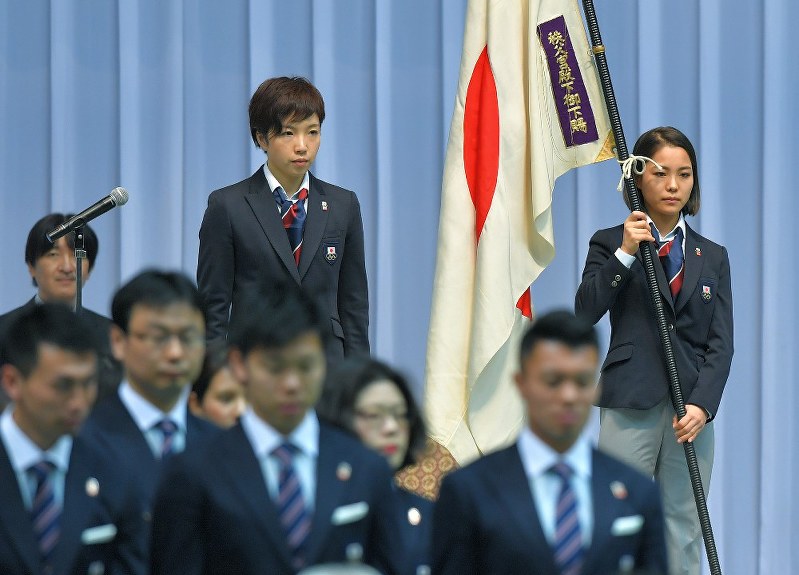 平昌五輪の日本代表選手団結団式で、決意表明を終えた小平主将(左)と、団旗を手に並ぶ旗手代行の高梨沙羅=手塚耕一郎撮影