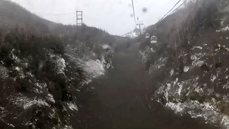 ゴンドラから乗客が撮影した、降灰などで覆われ黒くなった雪面=群馬県草津町で2018年1月23日、スキー客提供動画から