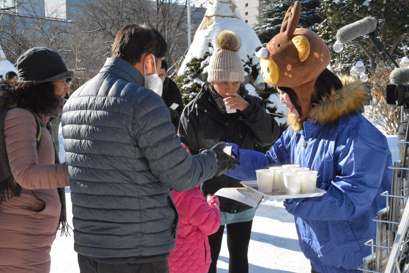 ホットミルクやパンフレットを配り、外国人観光客にPRする担当者=札幌市中央区で
