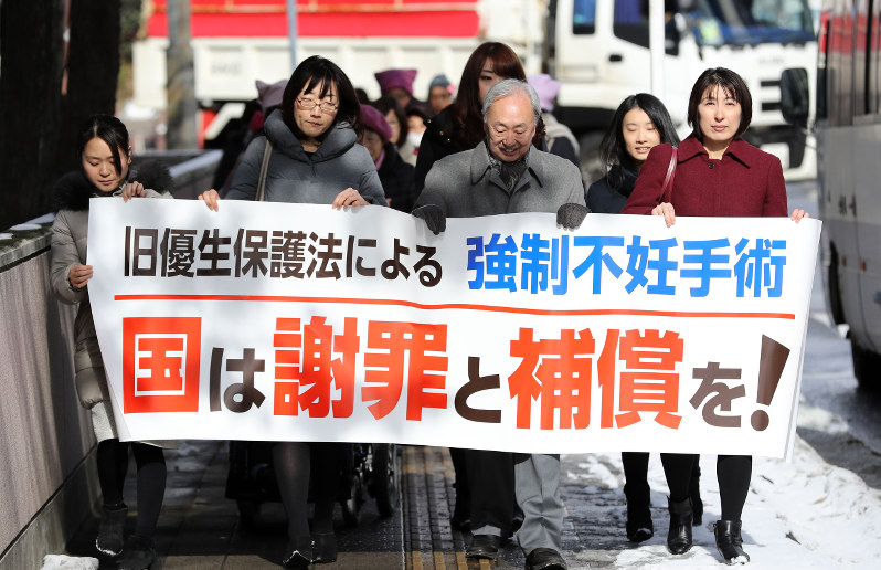 旧優生保護法の下で強制された不妊手術について国に損害賠償を求める提訴を前に、横断幕を持って仙台地裁に入る原告団ら=仙台市青葉区で、喜屋武真之介撮影