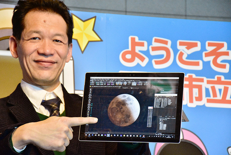 ライブ中継で音声解説を行う井上毅館長。手にするモバイル端末には今回の月食のシュミュレーション画像が映し出されている=兵庫県明石市人丸町の市立天文科学館で、浜本年弘撮影
