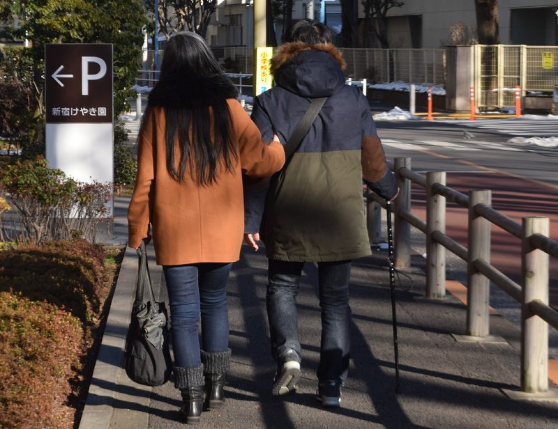 つえを使って歩く夫を支える妻(左)。「小室さんを批判できる人は、同じ立場ではいないと思います」