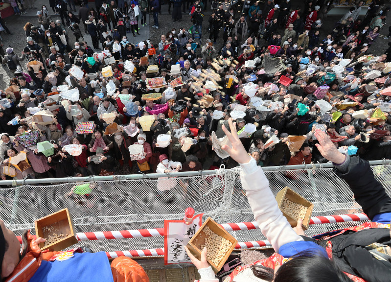 「福は内」とまかれた福豆を袋などを広げて受け止める参拝者ら=名古屋市中区の大須観音で2018年2月3日午前10時13分、兵藤公治撮影