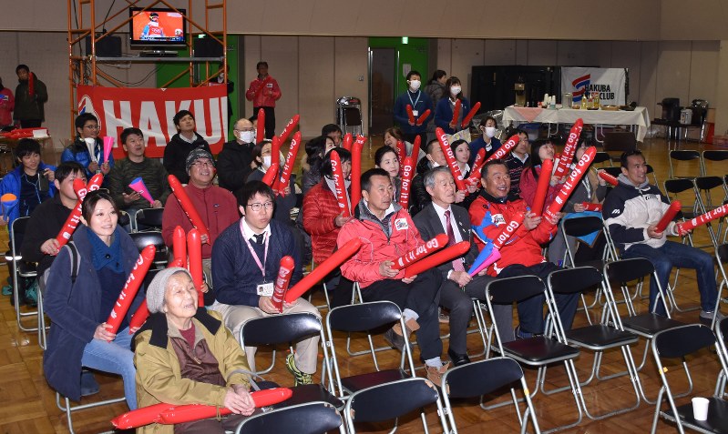 スティックバルーンを両手に持ち、西選手に声援を送る人たち=白馬村北城の村多目的ホールで