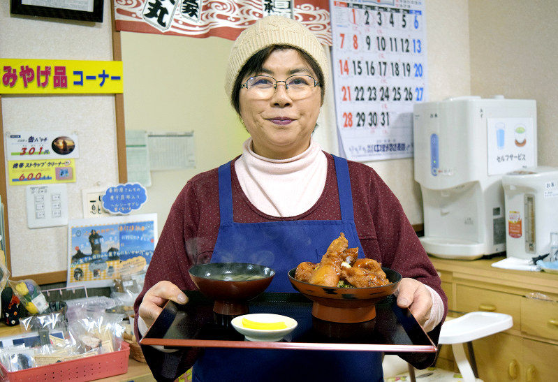 「どんこ唐揚げ丼」を手に笑顔を見せる赤沼秋子さん=岩手県宮古市田老の善助屋食堂で