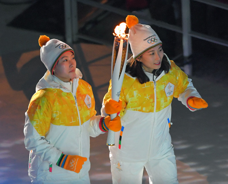 平昌五輪開会式で、聖火を持って走るアイスホッケー女子合同チーム「コリア」の北朝鮮のチョン・スヒョン(左)と韓国のパク・ジョンア=韓国・平昌五輪スタジアムで2018年2月9日午後10時6分、手塚耕一郎撮影