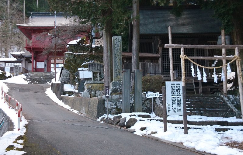 法華寺の山門(左奥)の前に、「吉良左兵衛義周公ここに眠る」と案内が立つ=諏訪市で