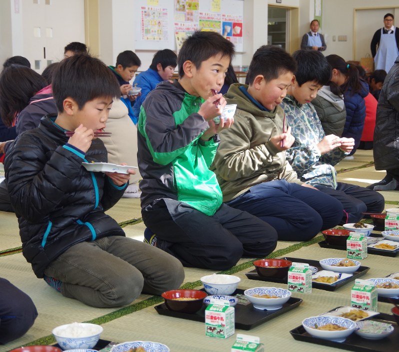 ござの上で正座をしながら給食を食べる児童