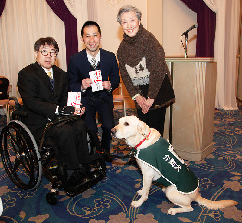 「国際ソロプチミスト宝塚」の正司泰子会長(右)から介助犬支援の目録を手渡された木村佳友さん(左)と介助犬「デイジー」、兵庫介助犬協会の北澤光大理事長(中央)=兵庫県宝塚市の宝塚ホテルで、高尾具成撮影