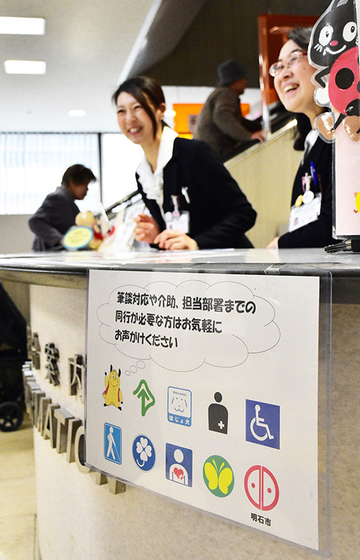 市役所の総合案内では障害者からの提案を生かし、筆談や同行などを求める利用者に「お気軽にお声かけください」と掲示し、呼び掛けている=兵庫県明石市役所で、浜本年弘撮影