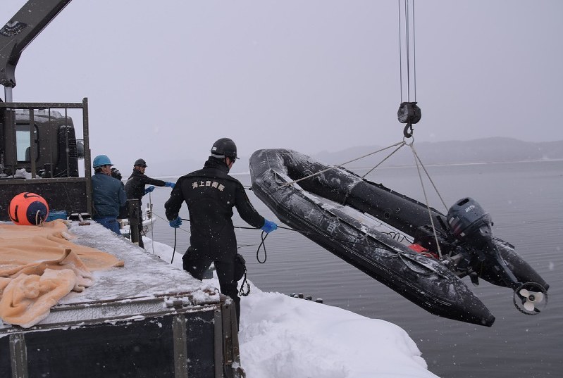 油の流出状況などを調べるためにボートの準備をする海上自衛隊員ら=青森県東北町の小川原湖で2018年2月21日午後4時42分、一宮俊介撮影