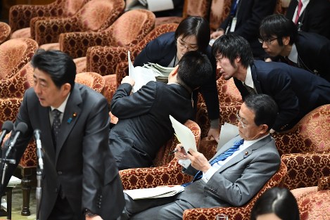 衆院予算委員会で裁量労働を巡る残業データ問題について安倍晋三首相（左手前）が答弁中、事務方に説明を受ける加藤勝信厚生労働相（中央）＝国会内で２０１８年２月２６日午後３時３９分、川田雅浩撮影