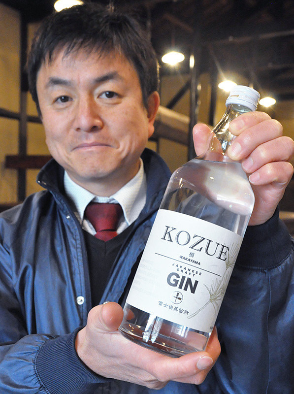 コウヤマキの香りを生かしたクラフトジン「槙-KOZUE-」を手にする西浦啓木さん=和歌山県海南市で、花澤茂人撮影