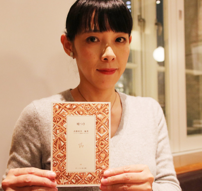 詩集絵本「嘘つき」を手にする高橋さん