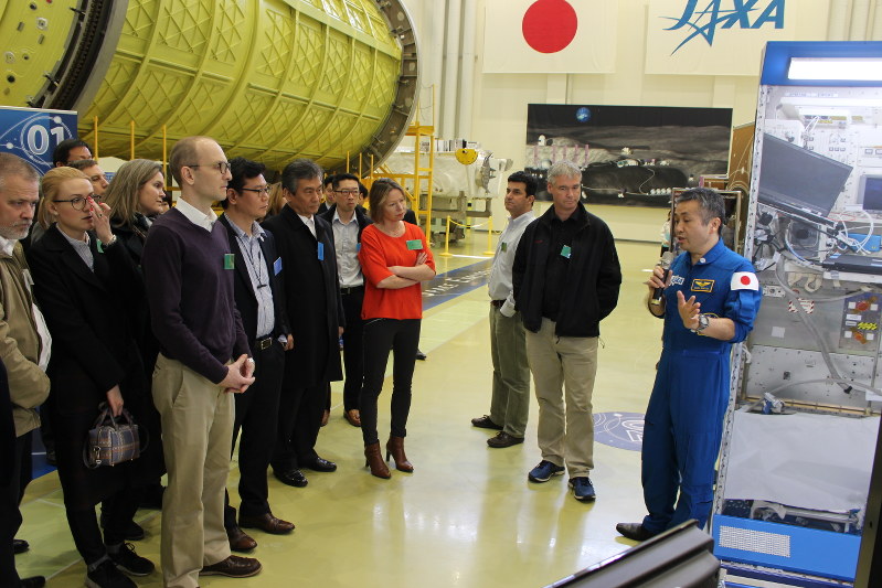 若田光一宇宙飛行士(右端)から日本の有人宇宙開発の試験設備について説明を受ける参加者=つくば市千現2で