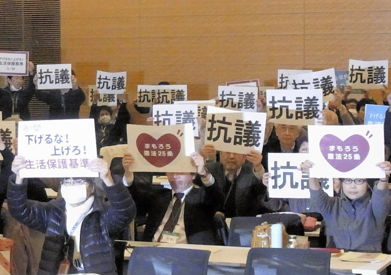 生活保護基準引き下げに反対する集会で、反対の意思表示をする参加者=東京都千代田区の衆院第1議員会館で昨年12月19日、西田真季子撮影