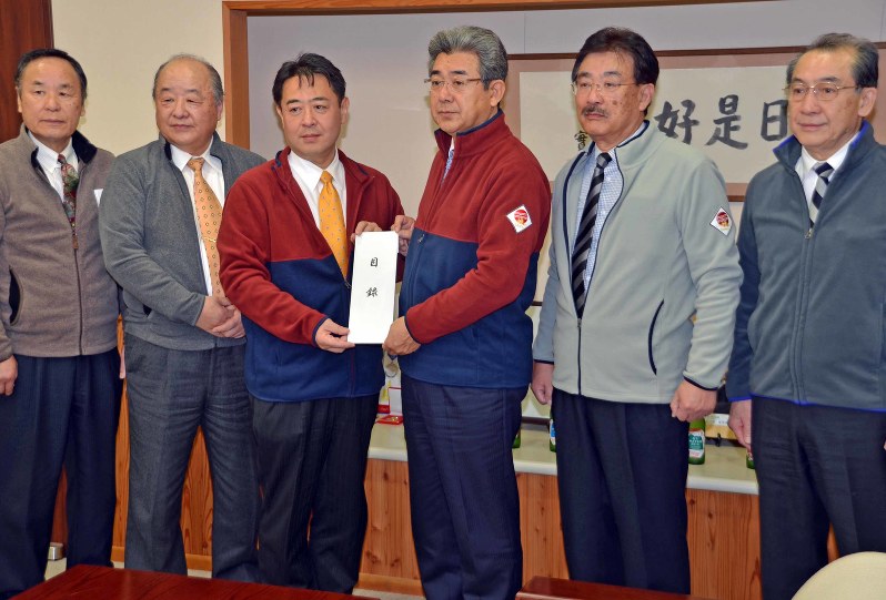 復興支援フリースを着用して義援金目録を柳田清二市長(左から3人目)に手渡す井上隆・観光協会長(同4人目)=佐久市役所で