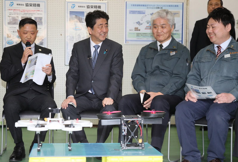生産設備メーカー「協栄精機」で小型無人機(ドローン)を前に、関係者らと話す安倍晋三首相(左から2人目)=福島県南相馬市で2018年3月10日(代表撮影)