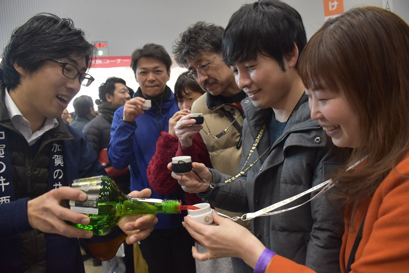 加賀の井酒造の店員と語らいながら試飲を楽しむ来場者たち=新潟市中央区の朱鷺メッセで