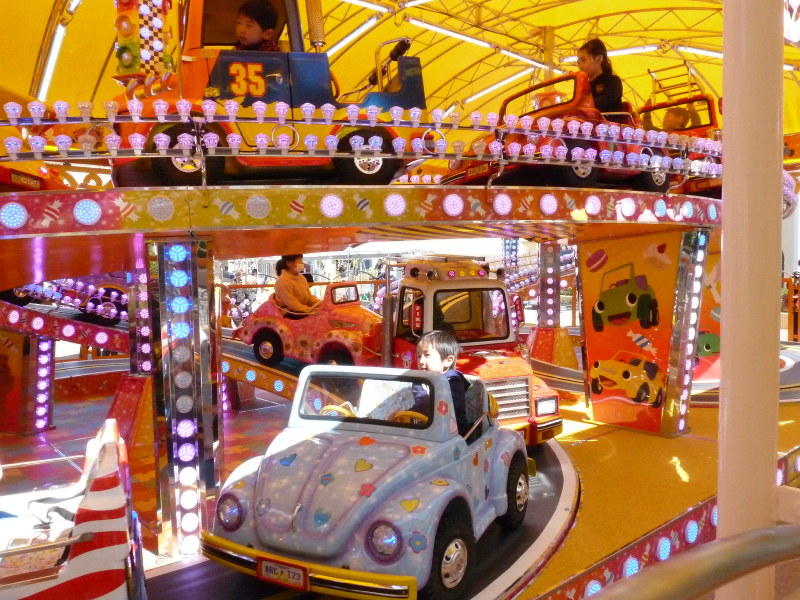 自動車型の遊具に乗りドライブ気分を楽しむ子どもたち=桑名市長島町のナガシマスパーランドで