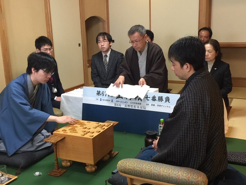 第67期王将戦七番勝負第6局で、封じ手の7七銀右を着手する豊島将之八段(手前左)。右は久保利明王将=長野県松本市の松本ホテル花月で2018年3月15日午前8時57分、丸山進撮影