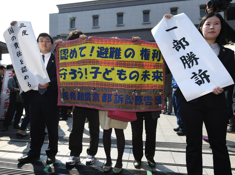 国と東京電力に損害賠償を求めた集団訴訟の判決で「一部勝訴」などと書かれた幕を掲げる弁護士ら=京都市中京区で2018年3月15日午前10時9分、小松雄介撮影
