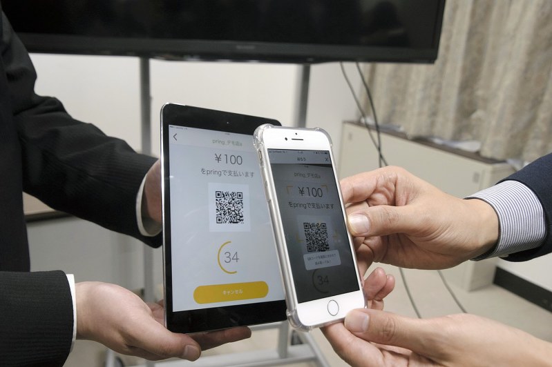 みずほと東邦銀の実証実験では入金したスマートフォン(右)を店舗のタブレット端末(左)の二次元コードにかざして決済する=横山三加子撮影