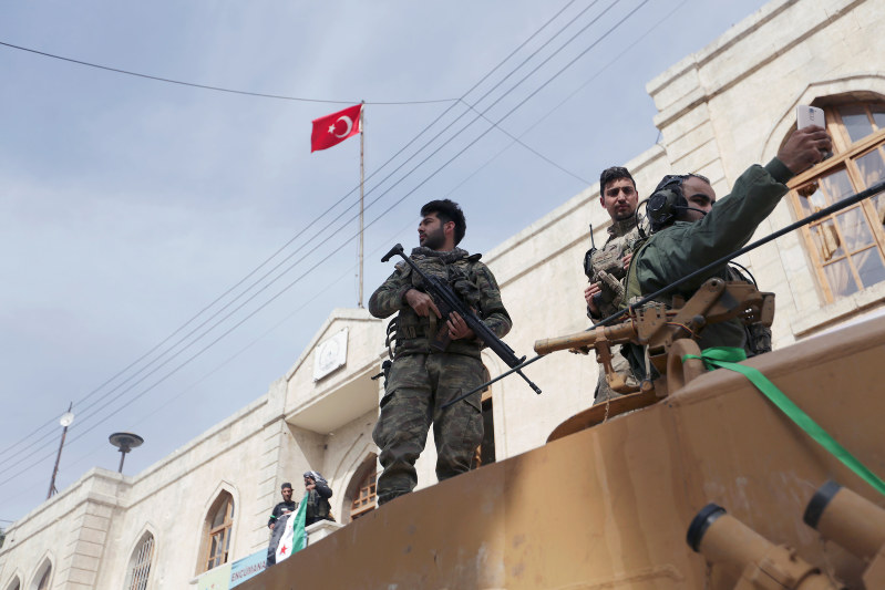 シリア北西部アフリンに進駐したトルコ軍と反体制派武装組織「自由シリア軍」の兵士。背後の建物にはトルコ国旗がはためく=18日、ロイター