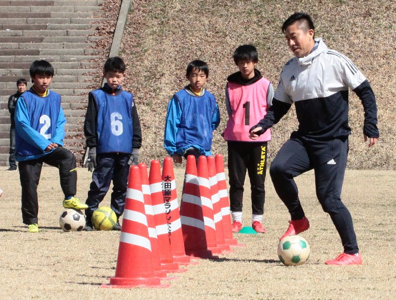 児童たちにドリブルの手本を披露する前園真聖さん(右)=大田原市ふれあいの丘多目的広場で