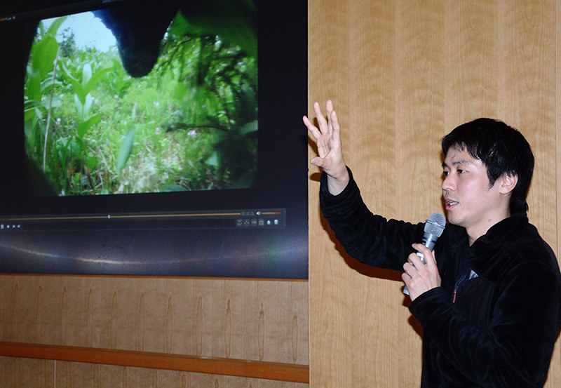 首輪に付けたカメラで撮影した動画を説明する後藤優介さん。映像の上部に映るのはツキノワグマの下顎=福井市の県立図書館で、岸川弘明撮影