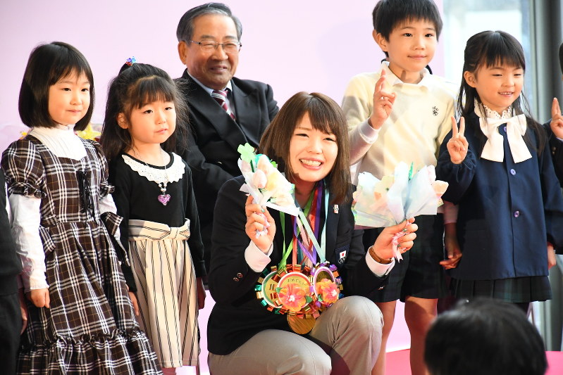 保育園児、幼稚園児から手作りのブーケと金メダルを贈られ笑顔の佐藤綾乃選手=高崎市高松町の高崎市役所で