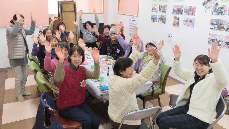 「100歳目指して人生バンザイ」と手を上げる認知症カフェの参加者=福岡県大牟田市で2018年2月1日